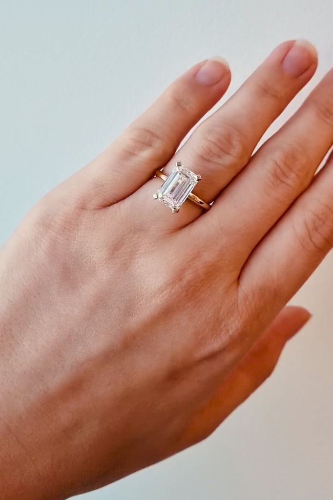 Gold ring with a lab diamond on a hand on a white background