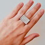 White gold ring with diamond stones on a hand on a white background