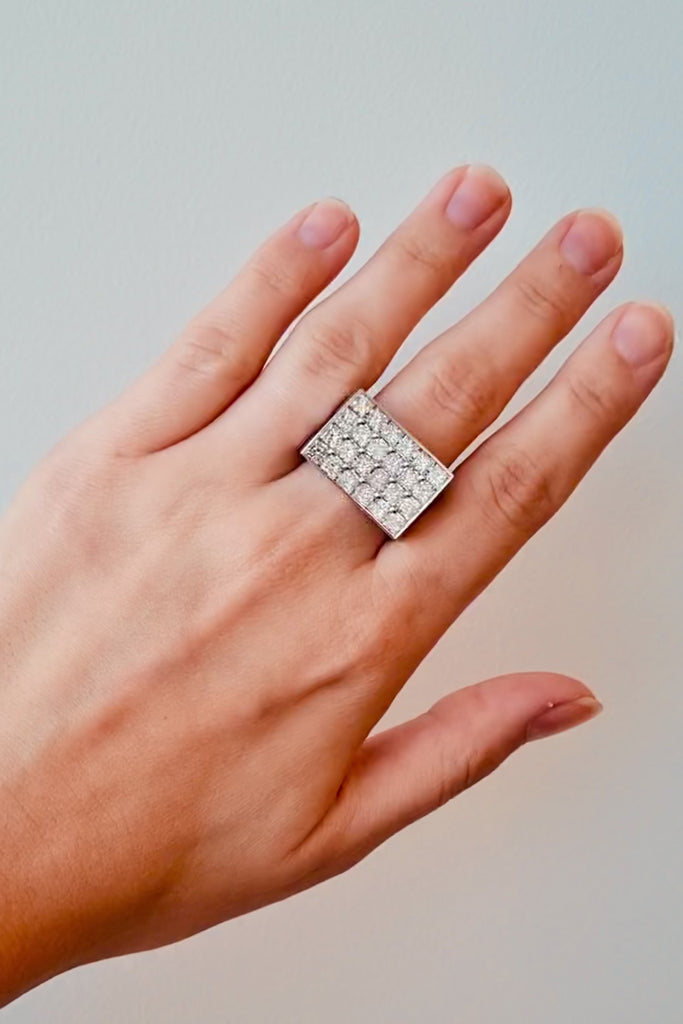 White gold ring with diamond stones on a hand on a white background