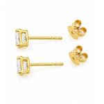 A pair of yellow gold stud earrings with oval clear diamonds and butterfly backings, displayed on a clean white background.